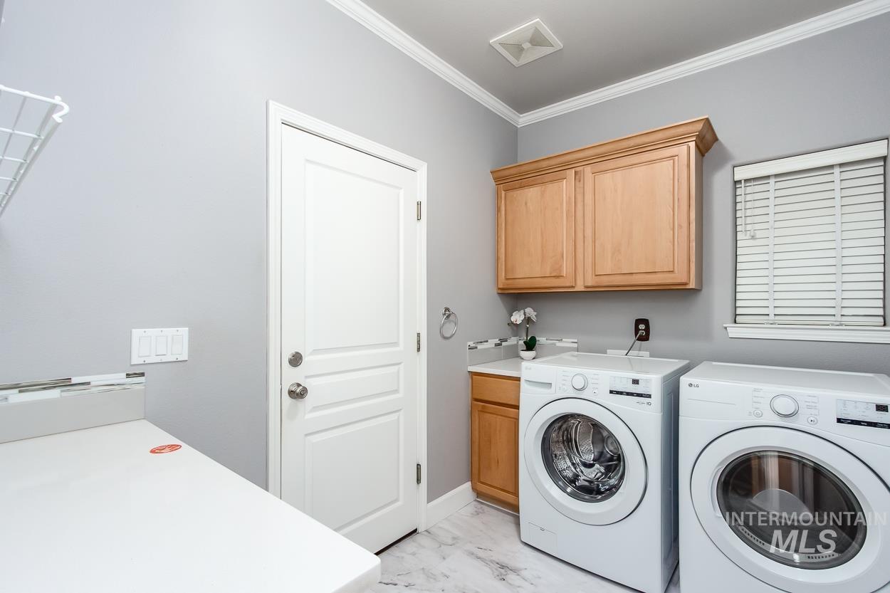 5674 North Heathrow Way Boise, ID 83713 - Photo 12 of 41 Dedicated laundry space featuring crown molding, wood-finish cabinetry, a white countertop, a tile backsplash, and wood-finish flooring