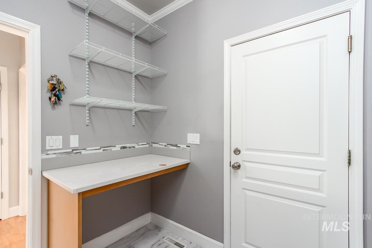 5674 North Heathrow Way Boise, ID 83713 - Photo 13 of 41 Entry area featuring a built-in light wood-finish desk with a light-toned countertop, a decorative tile backsplash, and three levels of white wire shelving