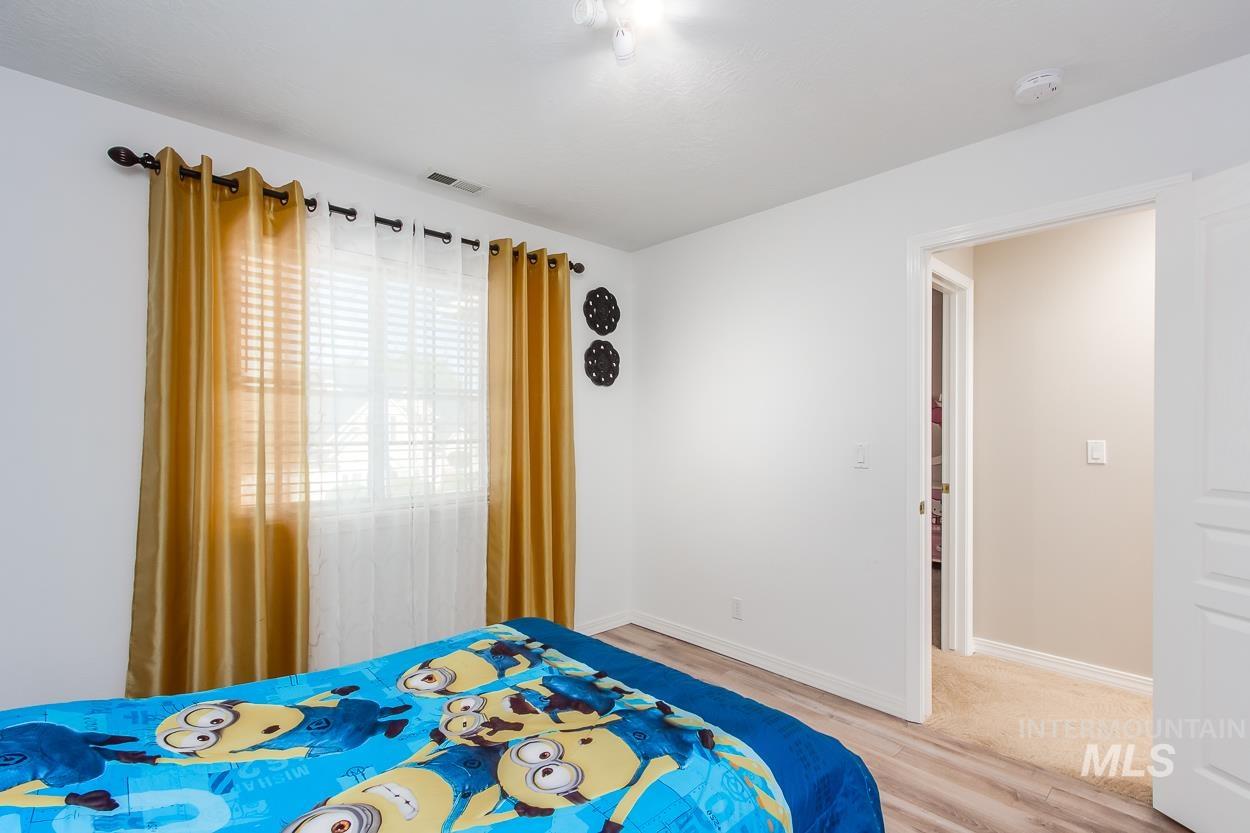 5674 North Heathrow Way Boise, ID 83713 - Photo 19 of 41 Bedroom featuring wood-finish flooring, white walls, and a window with horizontal blinds