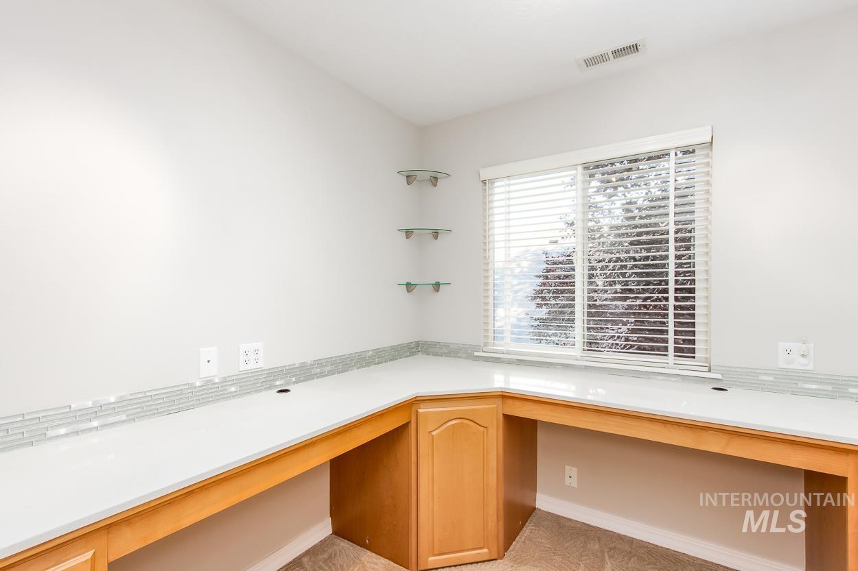 5674 North Heathrow Way Boise, ID 83713 - Photo 22 of 41 Built-in desk area featuring light wood-finish cabinetry, white countertops, and a glass tile backsplash
