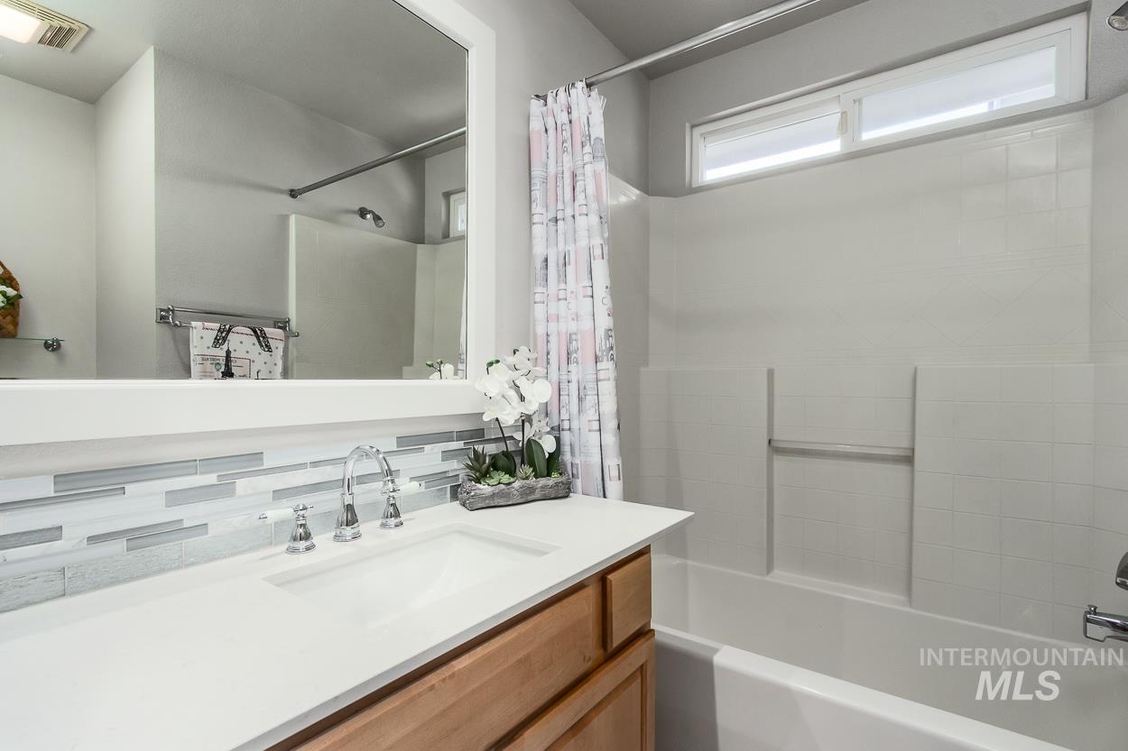 5674 North Heathrow Way Boise, ID 83713 - Photo 28 of 41 Bathroom featuring a spacious vanity with an integrated sink, polished chrome faucet, and a large framed mirror