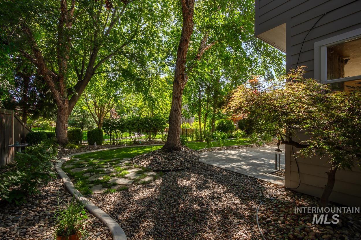 5674 North Heathrow Way Boise, ID 83713 - Photo 31 of 41 Landscaped backyard featuring mature trees, a concrete patio, and a stone walkway with grass inserts