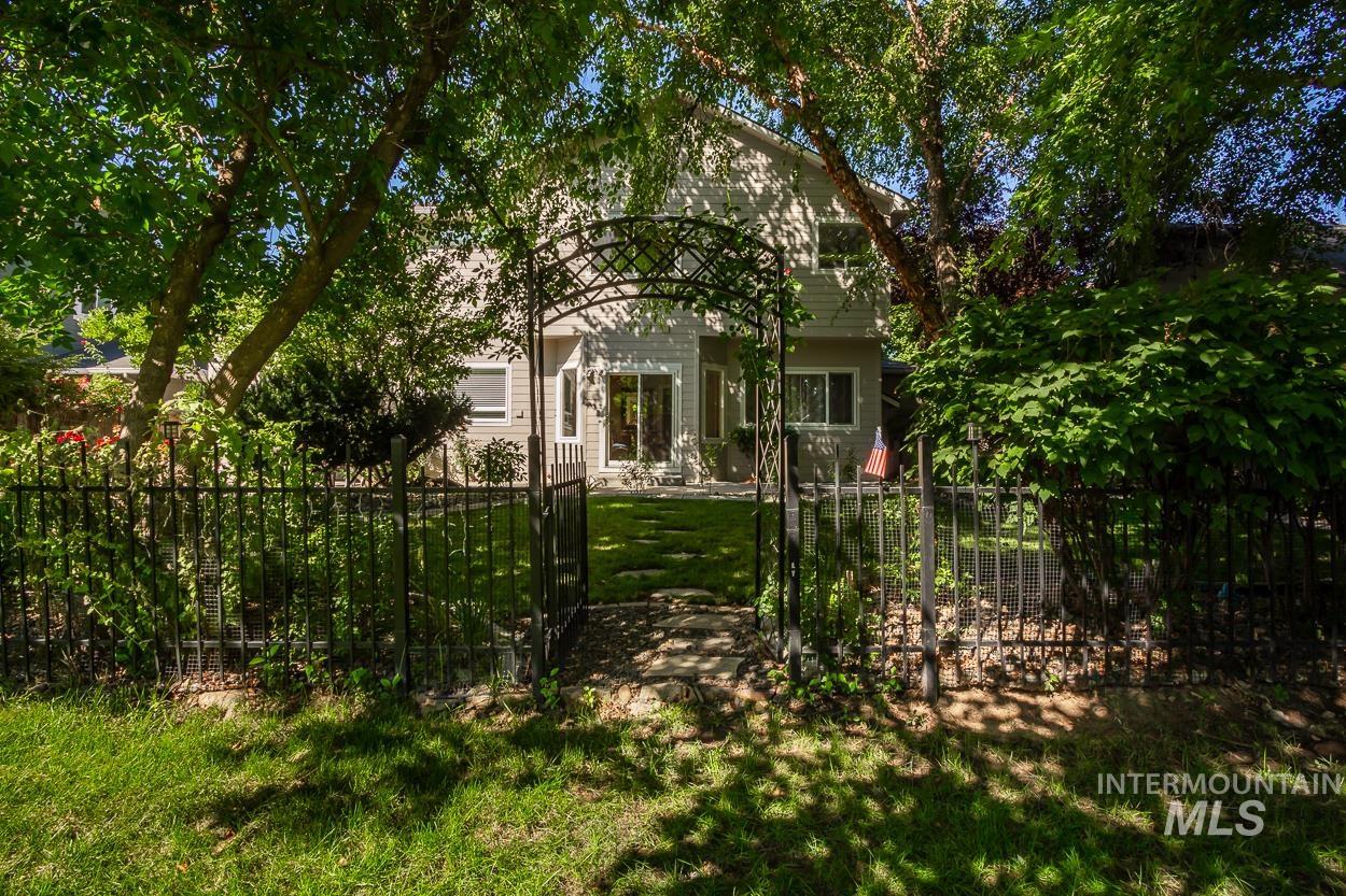 5674 North Heathrow Way Boise, ID 83713 - Photo 36 of 41 Enclosed backyard featuring an ornamental iron fence, a decorative garden archway, and mature perimeter trees providing natural shade