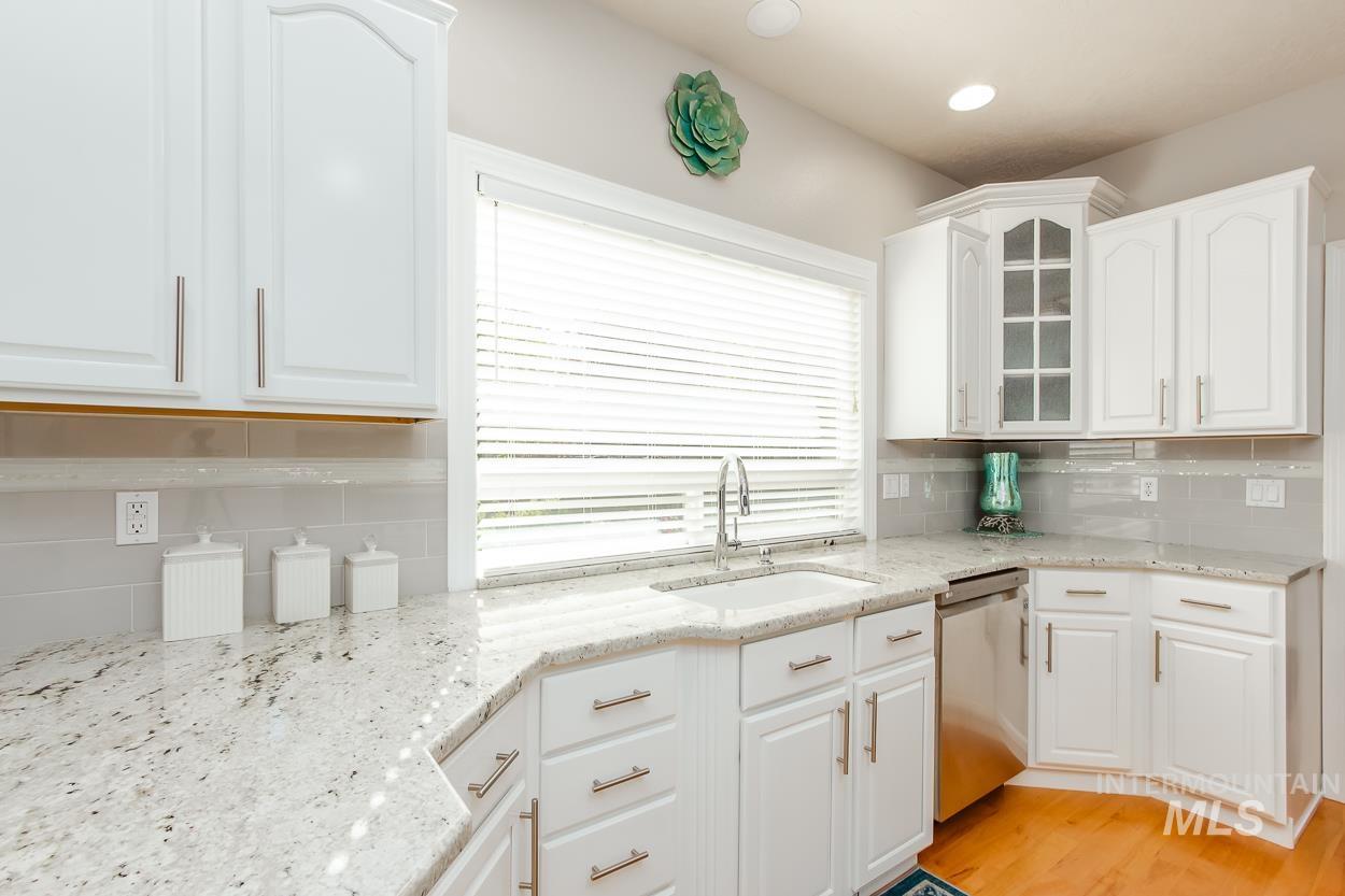 5674 North Heathrow Way Boise, ID 83713 - Photo 10 of 41 Kitchen featuring white cabinetry with brushed nickel hardware, light-toned patterned countertops, and a subway tile backsplash