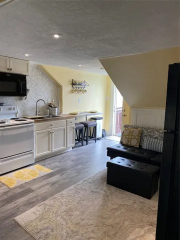 a living room with stainless steel appliances kitchen island granite countertop a sink and a stove