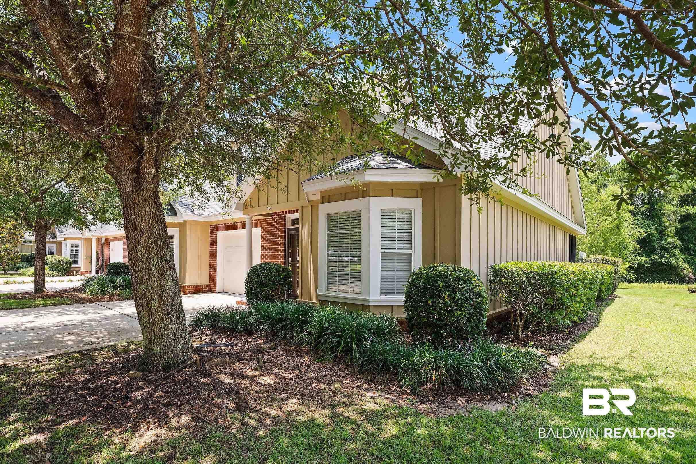 430 West Fort Morgan Road, Unit 704 Gulf Shores, AL 36542 - Photo 28 of 35 Exterior featuring a bay window, board and batten siding, brick accents, established landscaping, and a manicured lawn