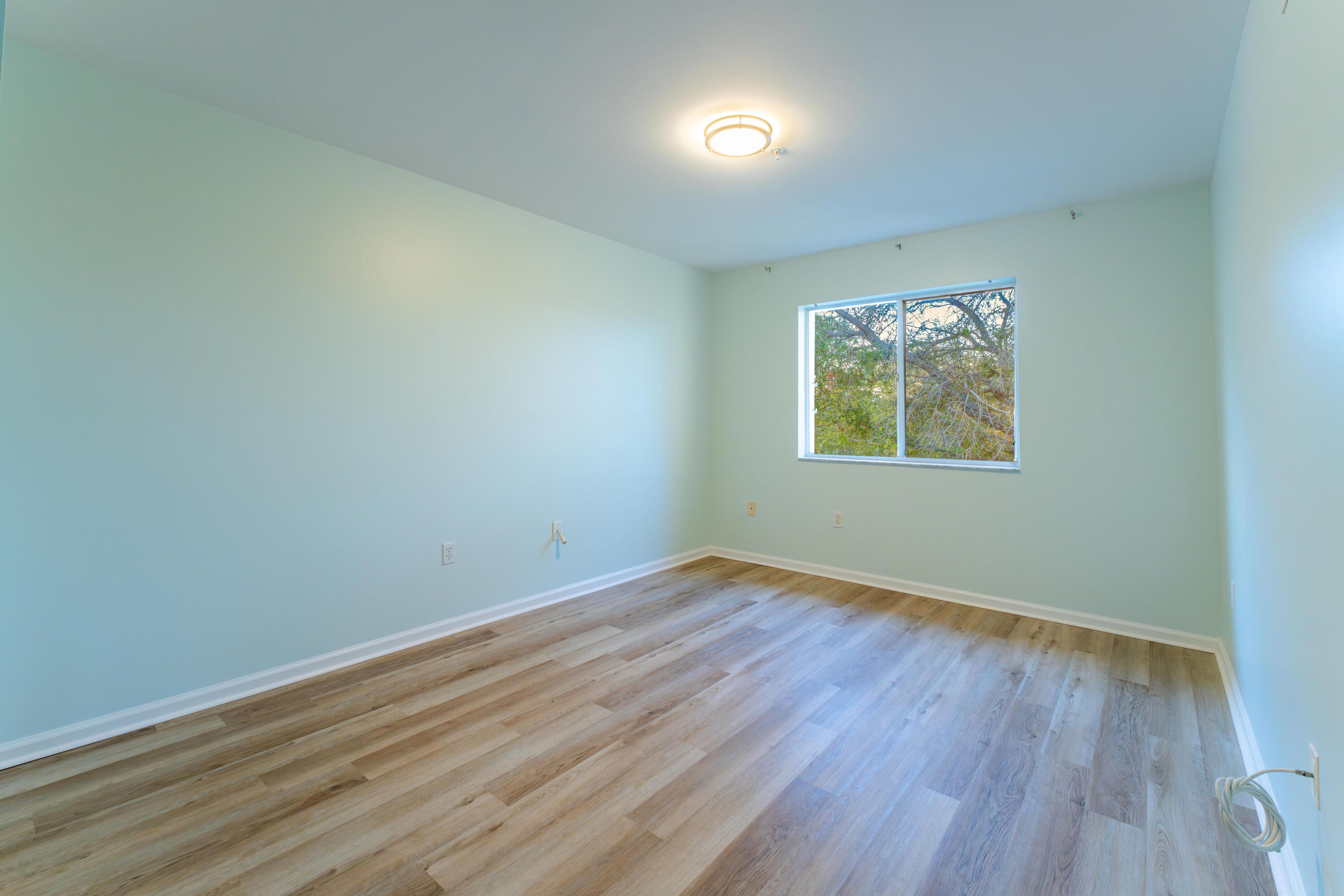 236 Village Boulevard, Unit 1304 Tequesta, FL 33469 - Photo 23 of 30 an empty room with wooden floor and windows
