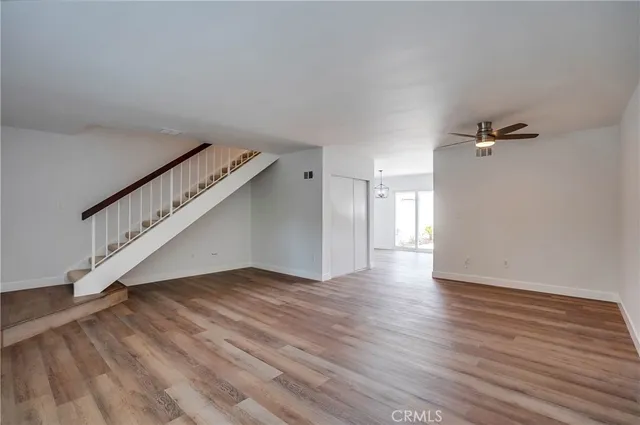 a view of an empty room with wooden floor and stairs