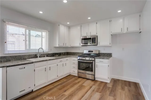 a kitchen with granite countertop white cabinets and white appliances