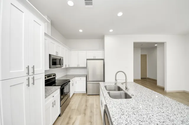 a kitchen with granite countertop a sink stainless steel appliances and cabinets
