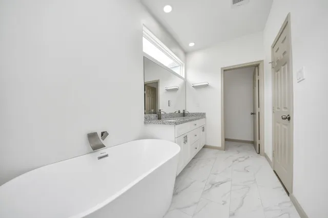 a bathroom with a tub sink and mirror
