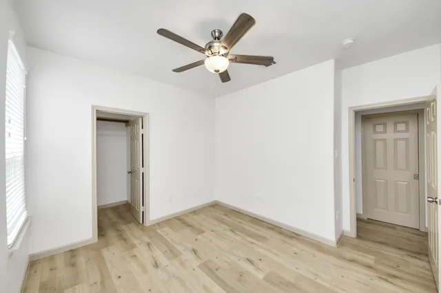 a view of empty room with wooden floor and ceiling fan