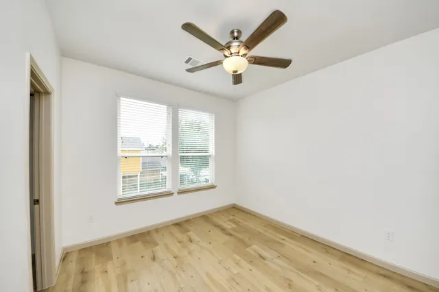 an empty room with wooden floor and windows