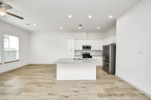a large kitchen with stainless steel appliances a large counter top and a refrigerator