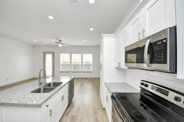 a kitchen with stainless steel appliances kitchen island granite countertop a stove and a sink