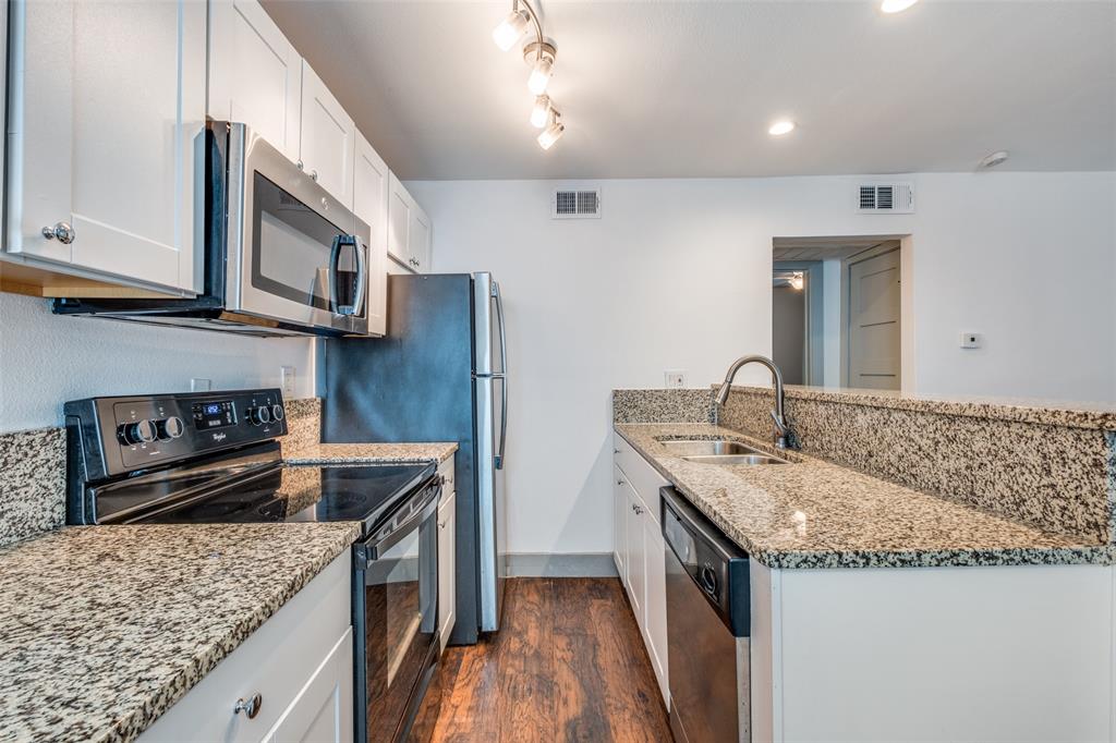 4633 Fairmount Street, Unit 109 Dallas, TX 75219 - Photo 9 of 14 Kitchen featuring granite countertops, wood-finish flooring, white cabinetry, stainless steel appliances, and track lighting