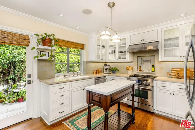 a kitchen with a stove a sink a center island and windows