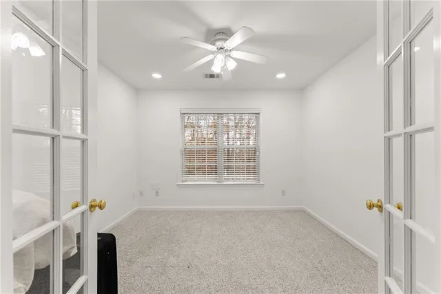 an empty room with chandelier fan and windows