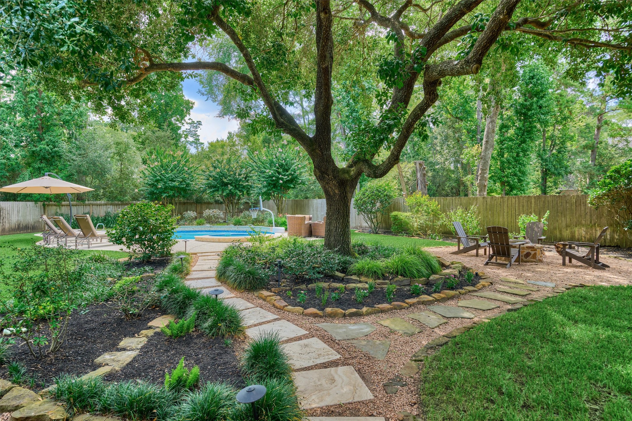 18 Treevine Court The Woodlands, TX 77381 - Photo 42 of 50 Mature trees and lush landscaping create a tranquil backyard retreat, complete with winding pathways to the pool and fire pit.