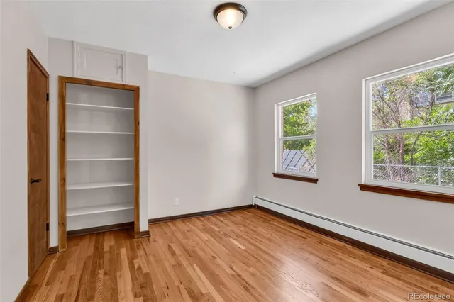 a view of empty room with wooden floor and fan