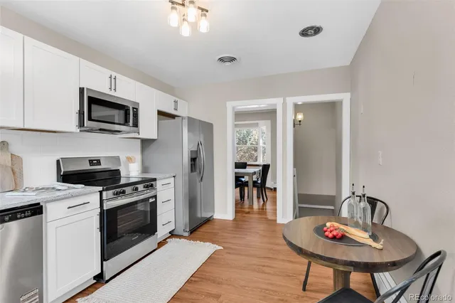 a kitchen with stainless steel appliances kitchen island granite countertop a stove a sink dishwasher a dining table and chairs with wooden floor