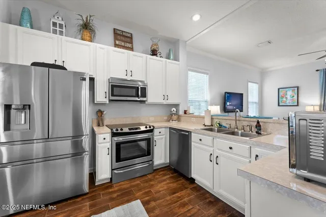 a kitchen with stainless steel appliances granite countertop a refrigerator stove a sink and a oven with wooden floor