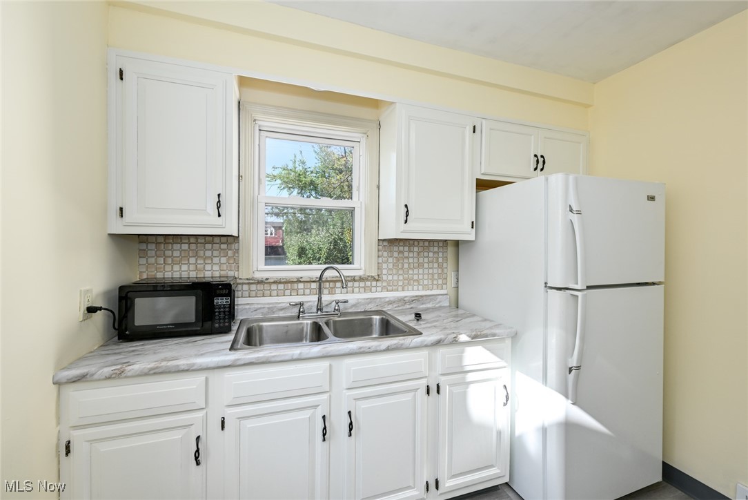 4033 Wyncote Road South Euclid, OH 44121 - Photo 5 of 25 Kitchen with decorative backsplash, sink, white cabinets, and white fridge