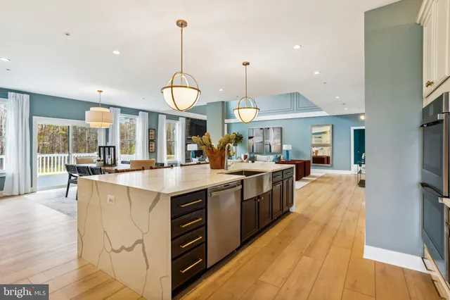 a kitchen with stainless steel appliances granite countertop a sink a stove and a wooden floors