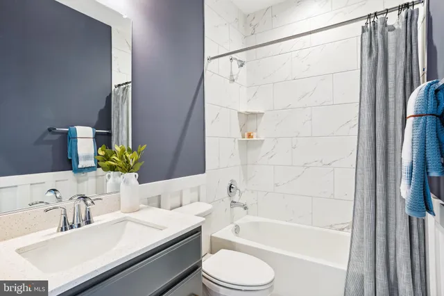a bathroom with a granite countertop bathtub sink vanity mirror and toilet