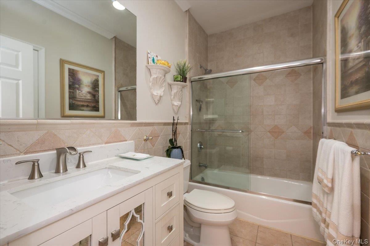 129 Round Swamp Road Huntington, NY 11743 - Photo 22 of 50 Full ensuite bathroom located on the first floor bathroom. Wood vanity with stone top, stone floor tile and tub / shower combination with sliding glass door.