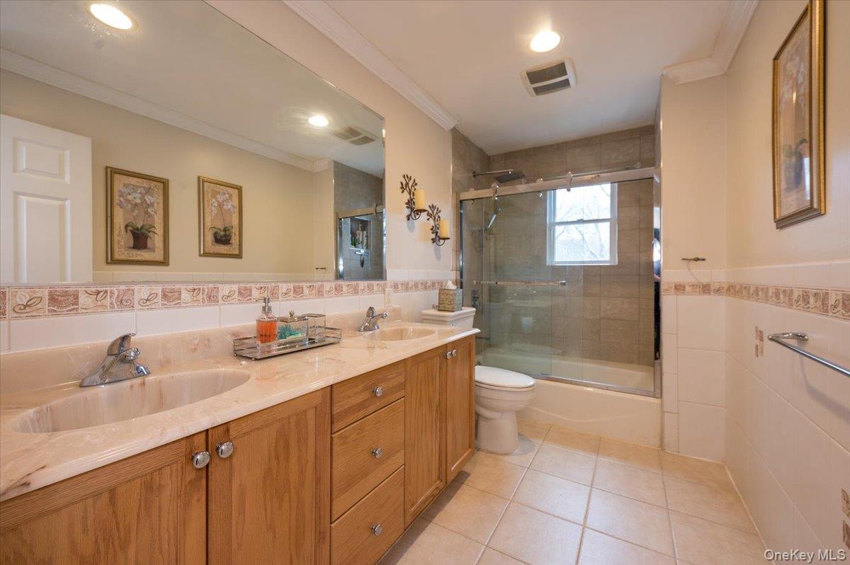 129 Round Swamp Road Huntington, NY 11743 - Photo 32 of 50 Large bathroom located on the second level with double wood vanity, tile flooring and tile enclosed tub / shower combination with glass sliding door.