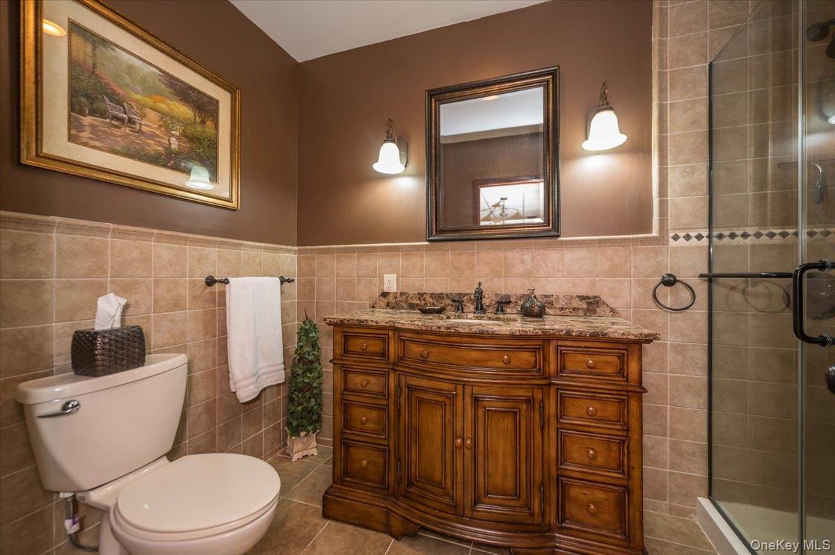 129 Round Swamp Road Huntington, NY 11743 - Photo 40 of 50 Full bathroom located in basement level with wood vanity, tile flooring and glass enclosed shower.