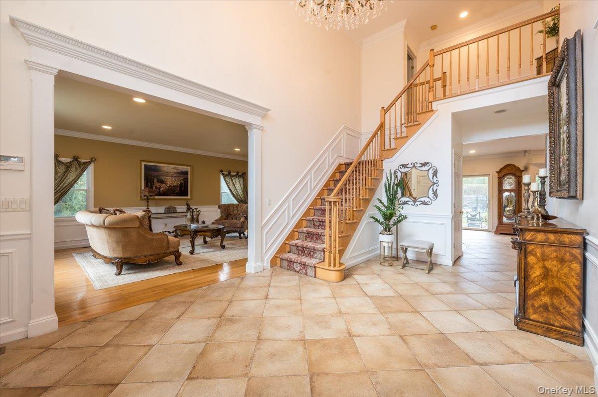 129 Round Swamp Road Huntington, NY 11743 - Photo 4 of 50 A large, two-story entry foyer features decorative moldings and overmantles on the doorways. and wainscoting on the walls. The space is lit by natural light, a statement chandelier and recessed lighting.