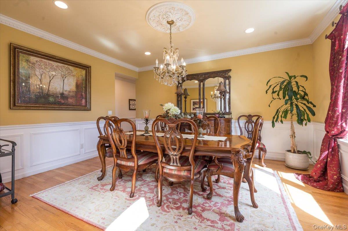 129 Round Swamp Road Huntington, NY 11743 - Photo 9 of 50 Dining room featuring wainscoting, light wood-style floors, a chandelier, and crown molding.