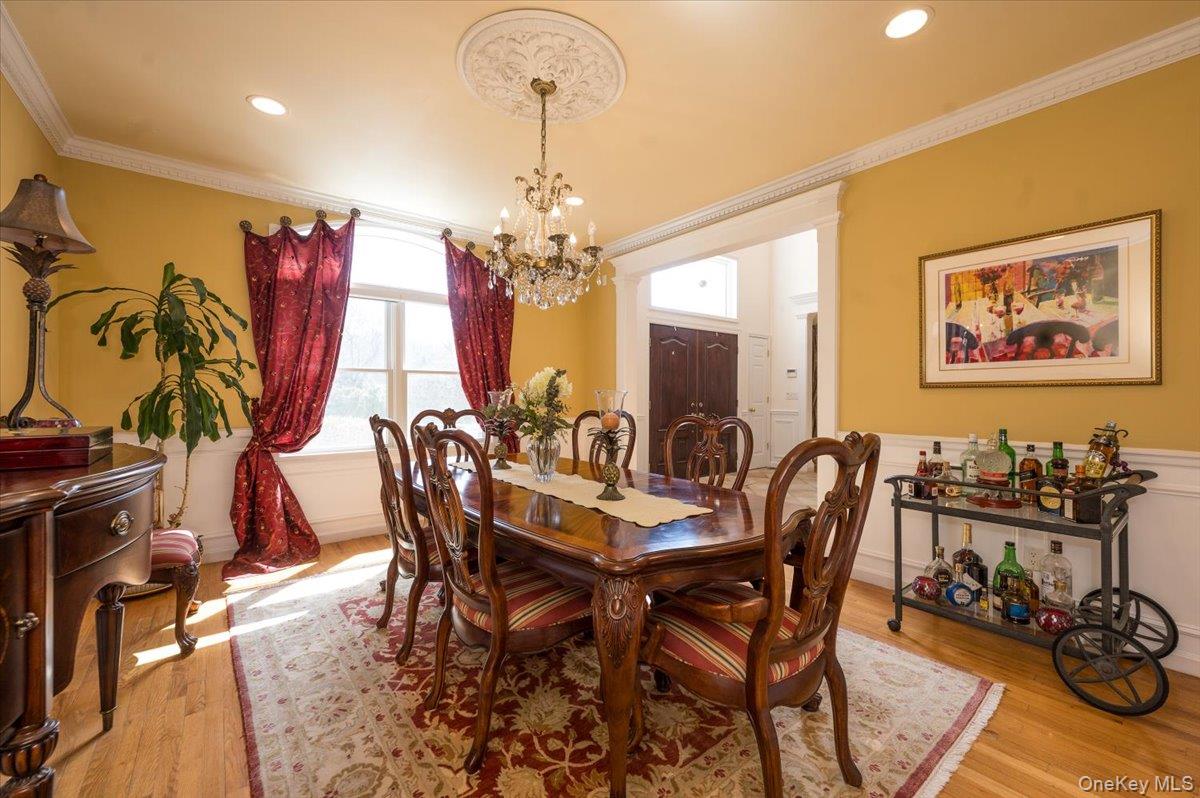129 Round Swamp Road Huntington, NY 11743 - Photo 10 of 50 Formal dining room with hardwood flooring, wainscoting, decorative crown moldings and a large statement window.