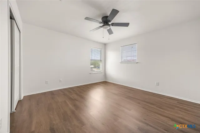 an empty room with wooden floor and windows