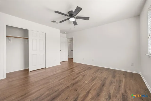an empty room with wooden floor and a ceiling fan