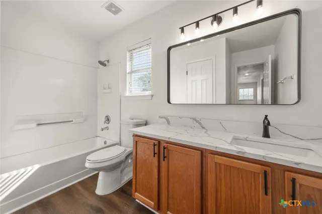 a bathroom with a granite countertop sink a toilet and a mirror