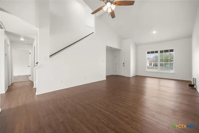 an empty room with wooden floor chandelier and windows