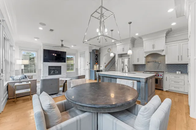 a kitchen with stainless steel appliances granite countertop a stove a sink a refrigerator a couch and a dining table with wooden floor