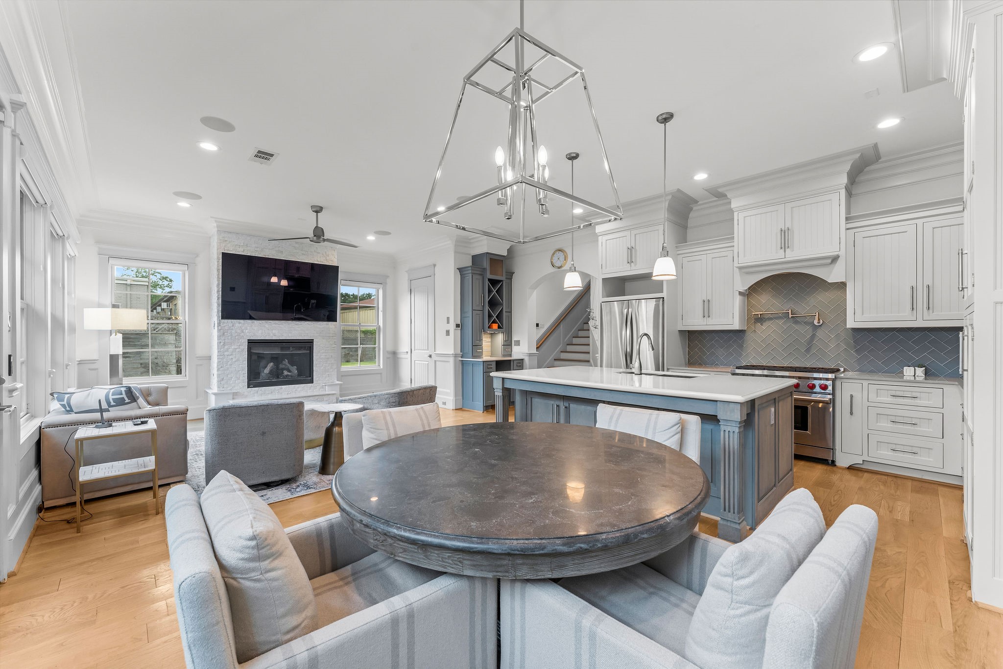 a kitchen with stainless steel appliances granite countertop a stove a sink a refrigerator a couch and a dining table with wooden floor