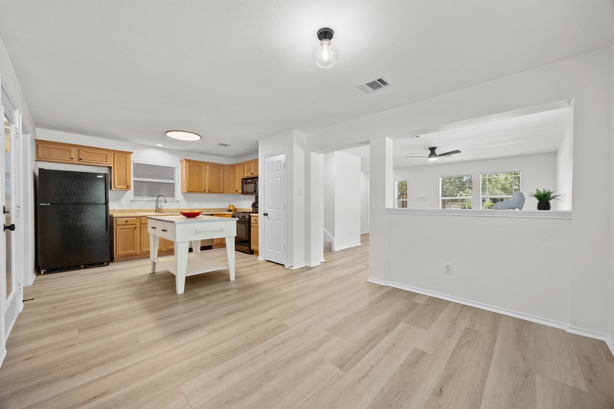 1818 Lost Maples Loop Cedar Park, TX 78613 - Photo 14 of 38 A well-lit kitchen with natural wood cabinetry and a central island flows seamlessly into an adjacent living area.