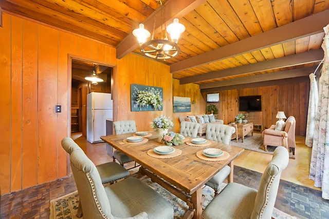 a dining room with wooden floor a chandelier a wooden table and chairs