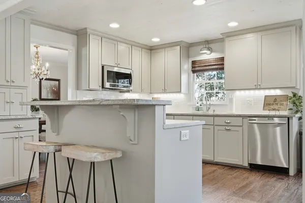 a kitchen with kitchen island granite countertop a sink cabinets and wooden floor