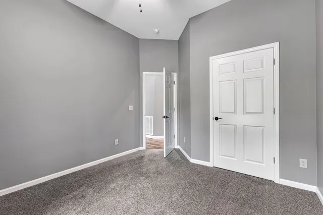 a view of an empty room with wooden floor and a ceiling fan