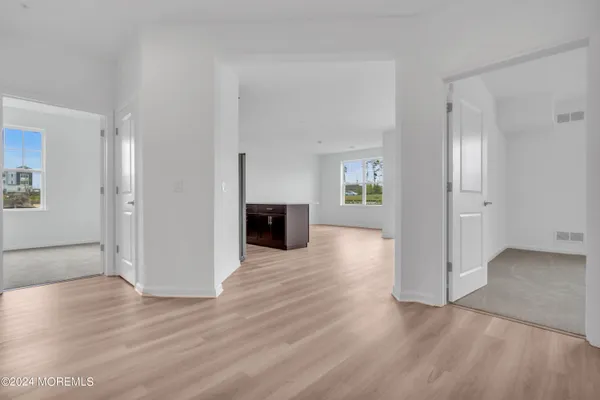 an empty room with wooden floor bathroom and windows