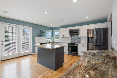 a large kitchen with stainless steel appliances granite countertop a stove refrigerator and a sink