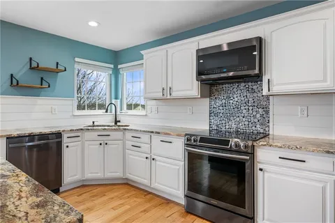 a kitchen with granite countertop a stove top oven microwave and cabinets