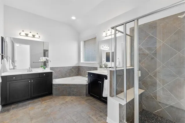 a spacious bathroom with a tub sink shower and mirror