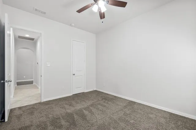 an empty room with a chandelier fan and windows